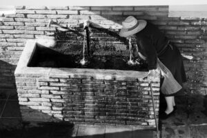 Fuente de rubite en blanco y negro y una señora mayor bebiendo de ella